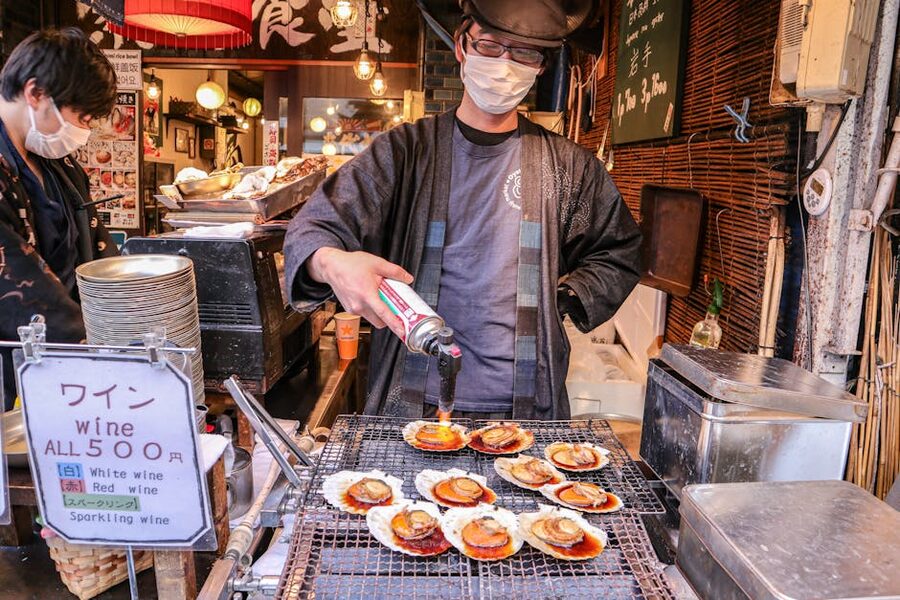Street food vendor grilling scallops with a torch in Japan