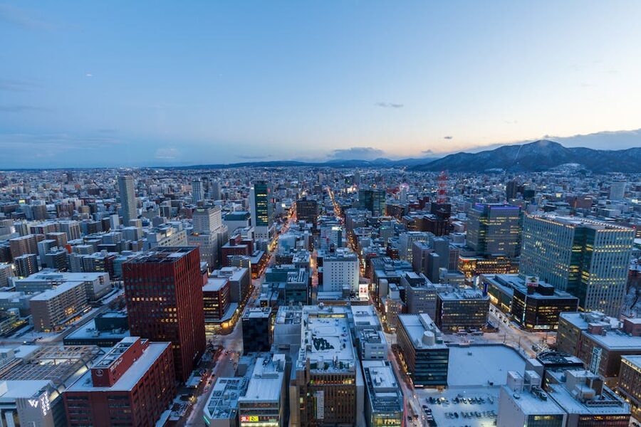 Aerial view of Sapporo Japan in winter at dusk with snow-covered buildings and mountains